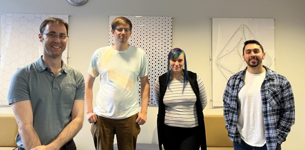Four people stood in a line, facing the camera